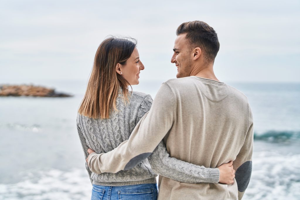 Mann und Frau halten sich in den Armen und lächeln sich an.