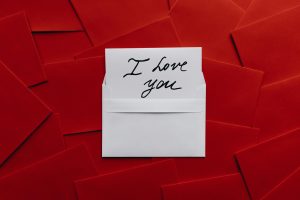 Ein handgeschriebener Brief mit der Schrift "Ich liebe dich" auf rotem Hintergrund.